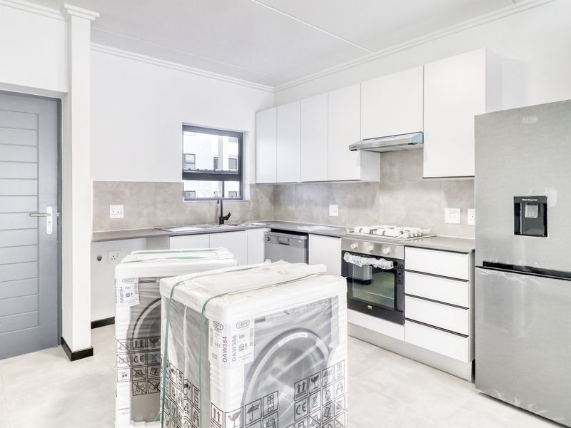 Modern kitchen featuring white cabinetry, tiled backsplash, built-in oven, gas hob, and extractor fan, with neutral tiled flooring throughout.