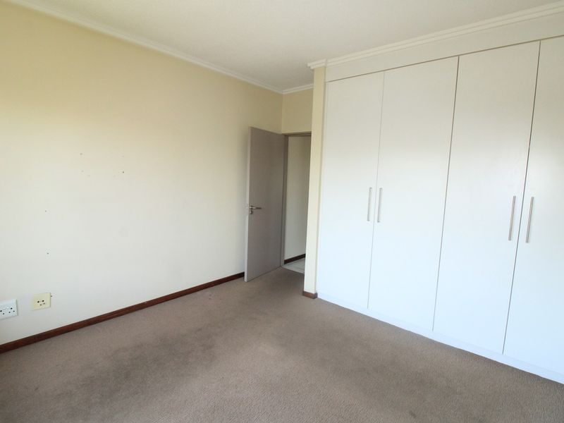 An empty bedroom featuring neutral walls, carpeted flooring, and ample built-in cupboard storage space.