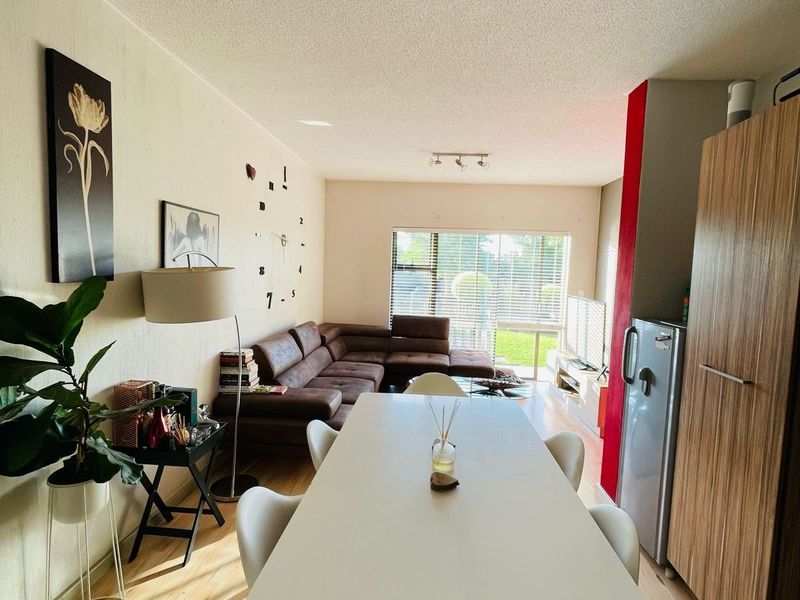 Open-plan living and dining area featuring laminate flooring, track lighting, and integrated cabinetry, creating a functional and connected living space.