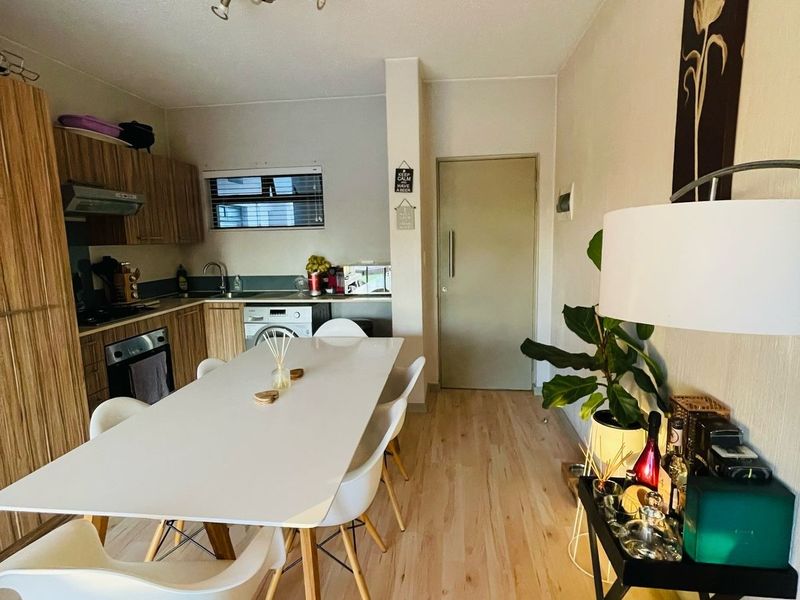 Open-plan kitchen and dining area featuring light wood-look laminate flooring, modern cabinetry, and integrated appliances, creating a functional and bright living space.