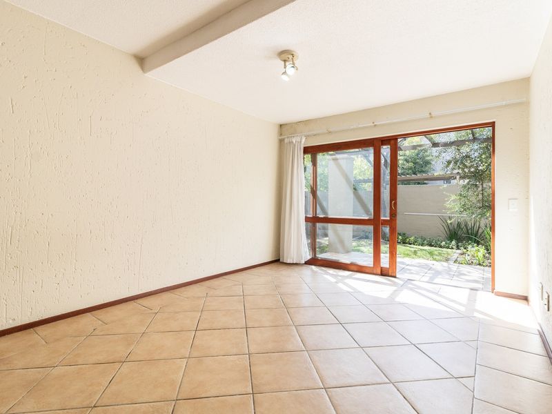 An empty living room featuring tiled flooring, textured walls, and a sliding glass door providing direct access to an outdoor patio area.