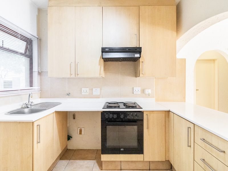 A functional kitchen featuring light wood cabinetry, laminate countertops, a built-in oven and stove, and a tiled backsplash, ready for modern updates.