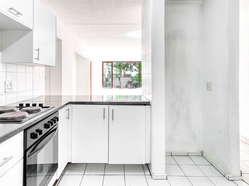 A functional kitchen featuring white cabinetry, a built-in oven with electric hob, tiled flooring, and a tiled backsplash, offering a clean, blank canvas.