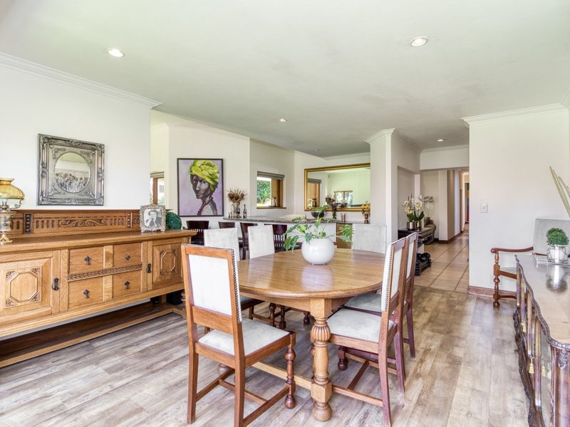 An open-plan dining area featuring laminate flooring, recessed downlighting, and a breakfast bar connecting to the kitchen space.