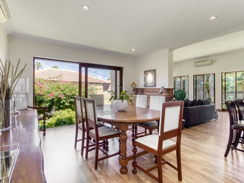 Spacious open-plan living and dining area featuring laminate flooring, recessed lighting, and large sliding glass doors providing seamless access to the garden.