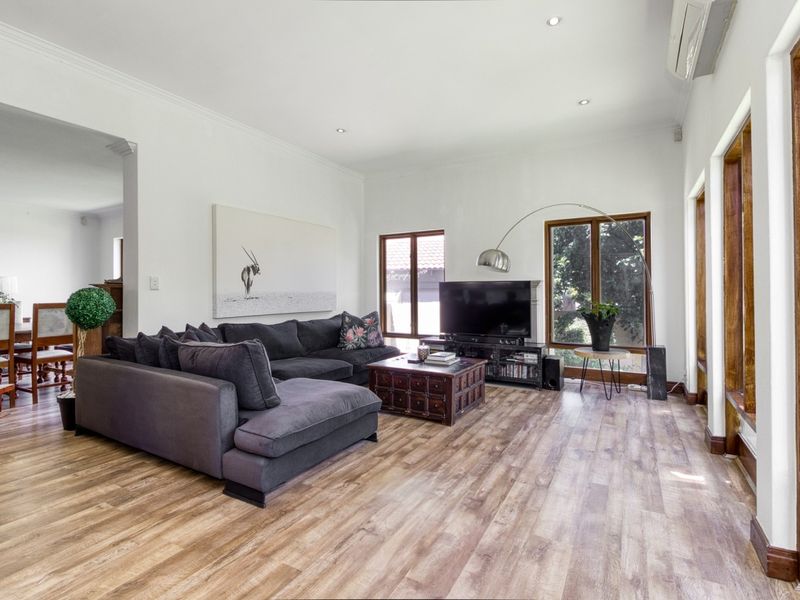 Spacious living room featuring modern laminate flooring, recessed downlighting, and large timber-framed windows, creating a bright and comfortable atmosphere.