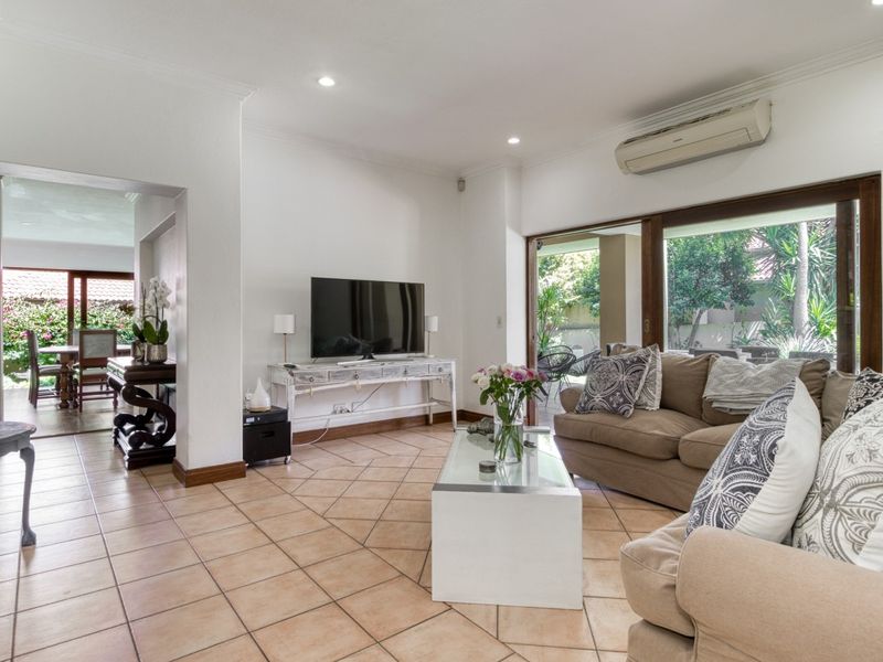 Spacious living room featuring tiled flooring, recessed lighting, and large sliding glass doors that provide seamless access to the outdoor patio area.