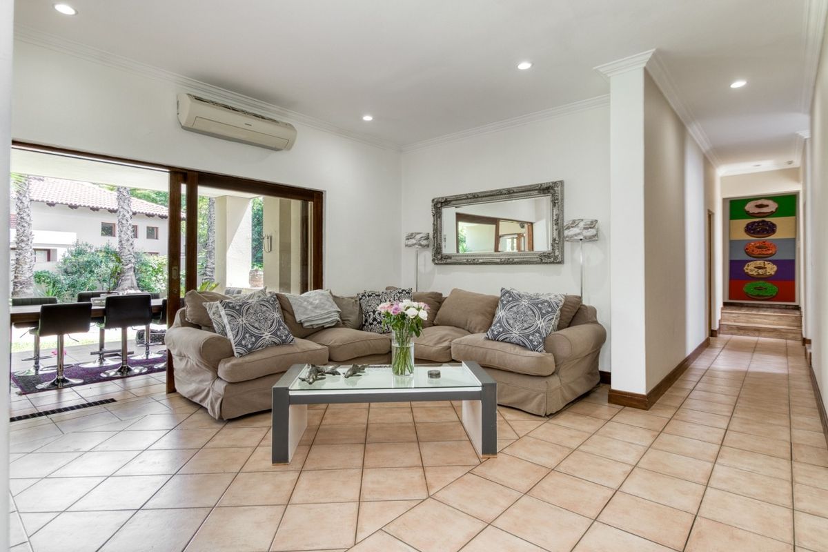 Spacious living room featuring tiled flooring, recessed lighting, and large sliding glass doors that provide seamless access to the outdoor patio area.