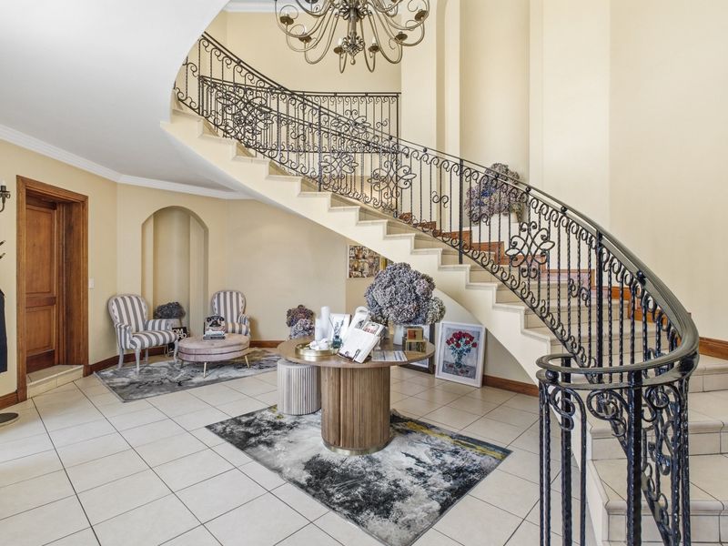 Grand entrance foyer featuring a sweeping curved staircase with ornate wrought iron balustrade and elegant tiled flooring.