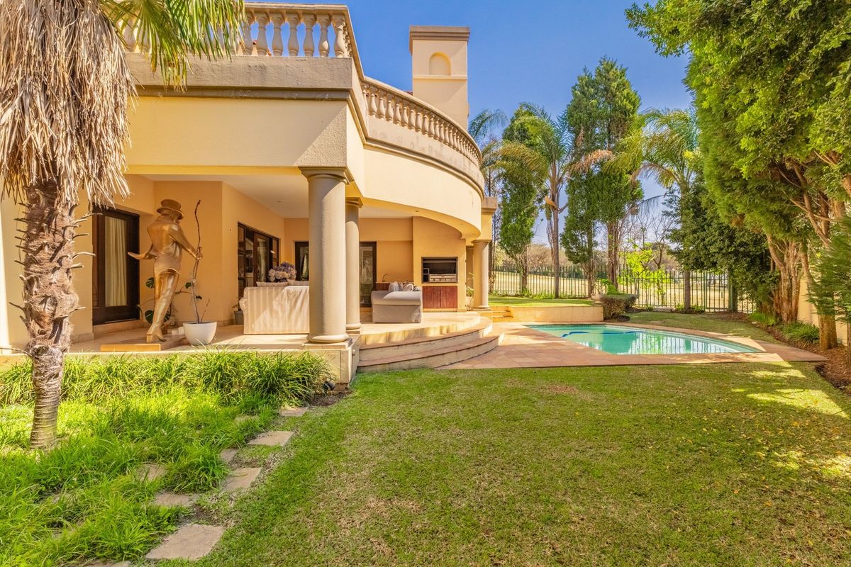 Rear exterior view featuring a covered patio with built-in braai, a swimming pool, and a landscaped garden with a curved architectural facade.