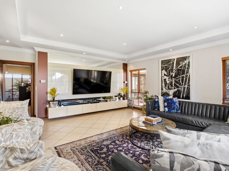 Spacious living room featuring tiled flooring, recessed ceiling lighting, and a custom built-in media console with integrated storage.