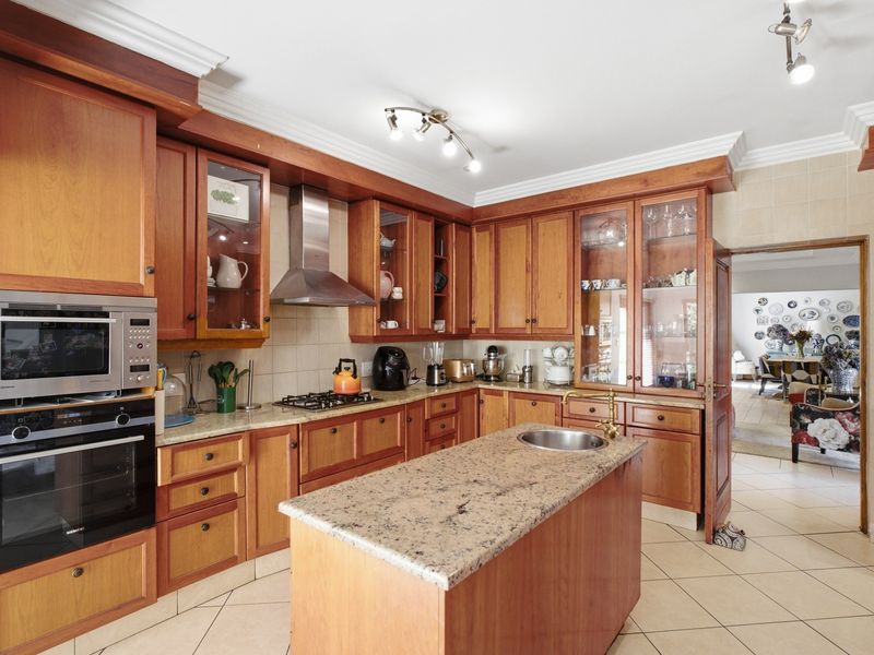 A traditional kitchen featuring warm wooden cabinetry, granite countertops, a central island with a prep sink, and integrated stainless steel appliances.