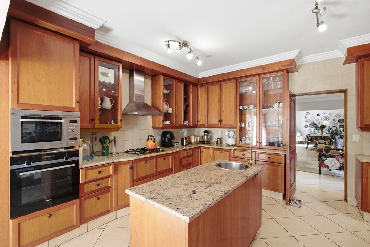 A traditional kitchen featuring warm wooden cabinetry, granite countertops, a central island with a prep sink, and integrated stainless steel appliances.