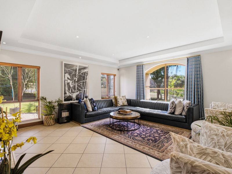 Spacious living room featuring tiled flooring, a recessed ceiling with downlights, and a large arched window providing natural light and garden views.