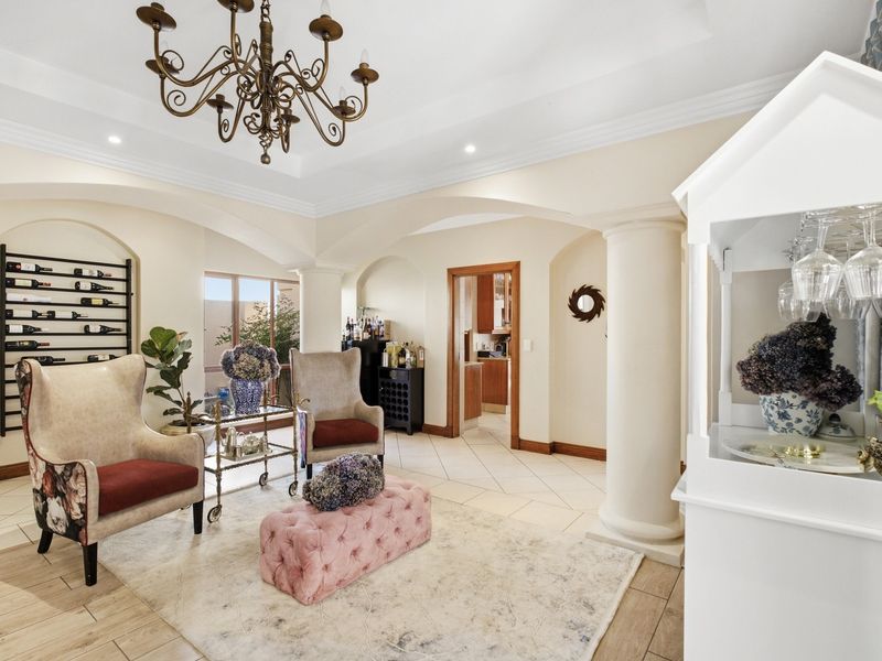 Elegant living area featuring architectural archways, decorative columns, recessed lighting, a classic chandelier, and built-in wine storage with tiled flooring.