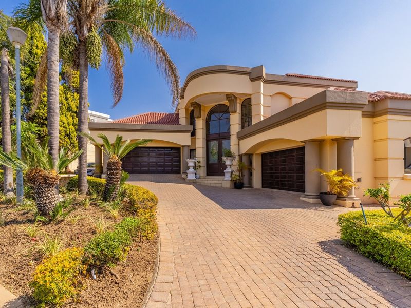 A well-maintained double-story residence featuring a paved driveway, double garage, and an elegant arched entrance with established garden landscaping.