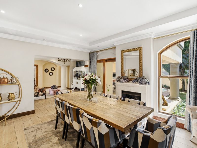 Elegant dining room featuring a fireplace, crown molding, recessed lighting, and large arched windows overlooking the outdoor area.