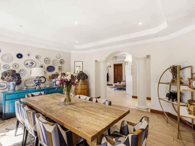 Spacious dining room featuring elegant columns, an arched entryway, recessed ceiling details, and tiled flooring, creating a sophisticated and inviting atmosphere.