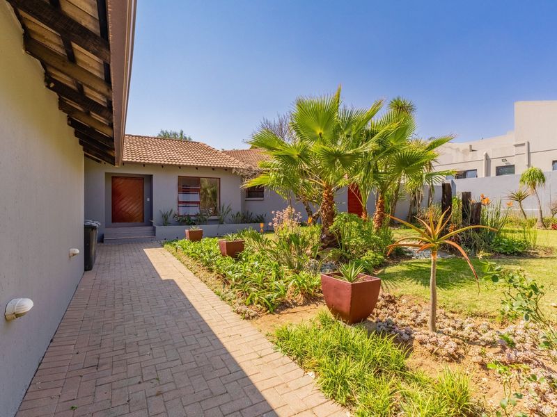 A well-maintained rear garden featuring a paved walkway, established landscaping, and a secure boundary wall, providing a pleasant outdoor space.