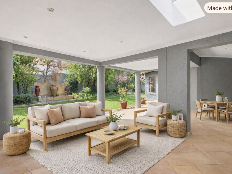 Spacious covered patio featuring tiled flooring, recessed lighting, and a skylight, overlooking a landscaped garden with a built-in water feature.