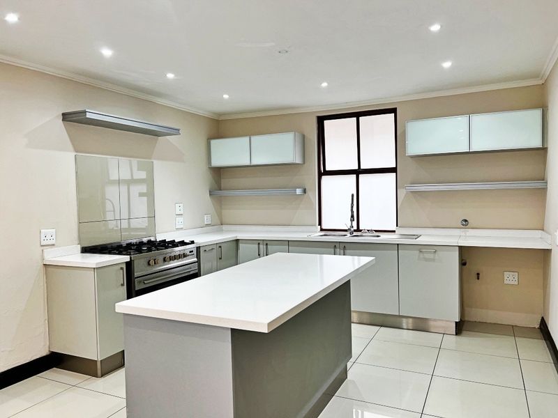 Modern kitchen featuring a central island, quartz countertops, gas stove, and ample built-in cabinetry with a clean, neutral aesthetic.