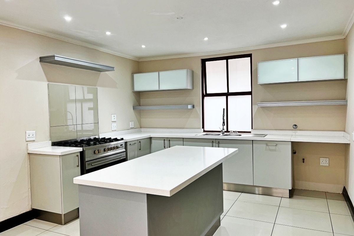Modern kitchen featuring a central island, quartz countertops, gas stove, and ample built-in cabinetry with a clean, neutral aesthetic.
