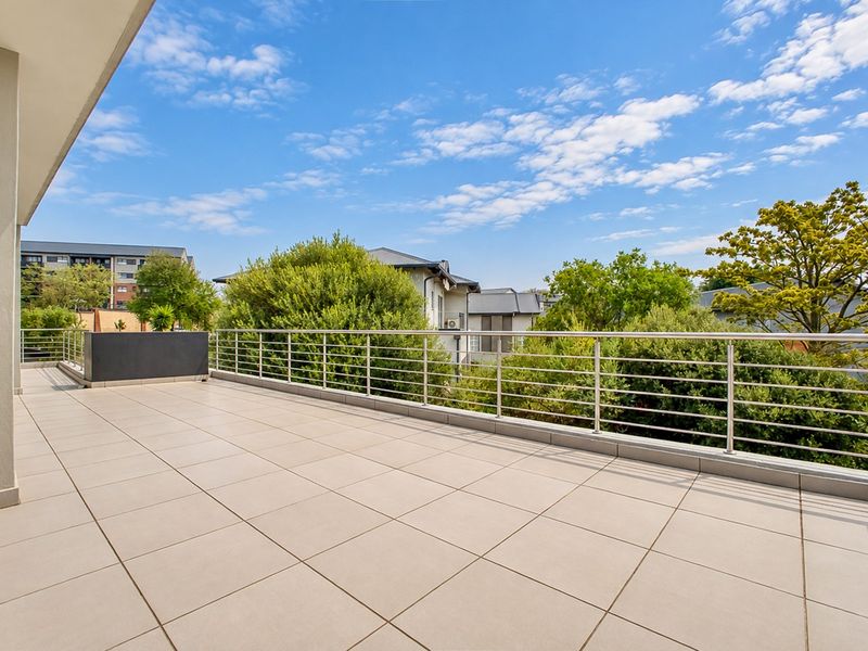 Spacious, well-maintained balcony featuring modern tiled flooring, a sleek stainless steel balustrade, and a built-in planter box with pleasant neighbourhood views.
