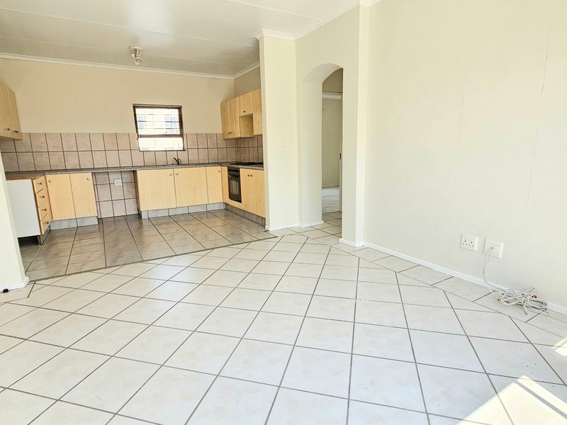 An open-plan living and kitchen area featuring tiled flooring, built-in cabinetry, and a built-in oven, offering a functional and versatile living space.