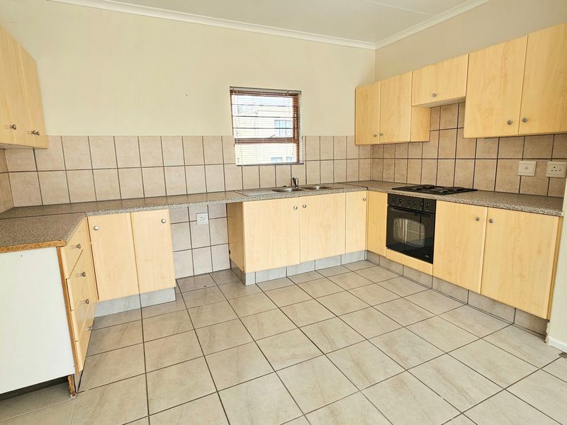 A functional kitchen featuring light wood laminate cabinetry, granite countertops, tiled backsplash, and built-in oven with hob.