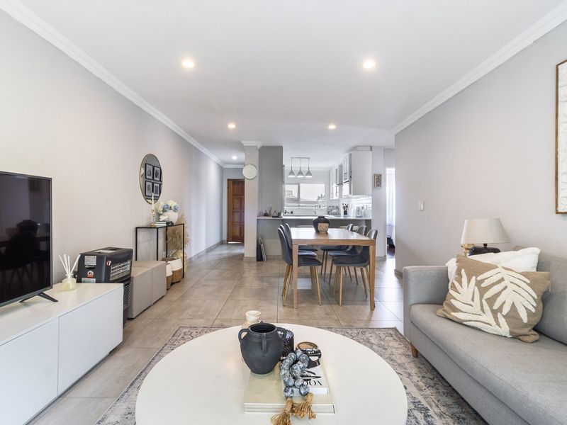 Spacious open-plan living and dining area featuring tiled floors, recessed lighting, and a modern kitchen with a breakfast island.