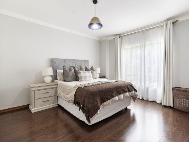 A well-maintained bedroom featuring dark laminate flooring, built-in wardrobes, and elegant cove cornicing, offering a bright and comfortable living space.