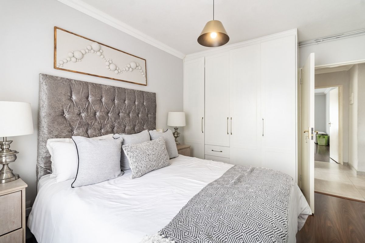 A well-maintained bedroom featuring built-in cupboards, laminate flooring, and decorative coving, offering a clean and functional living space.