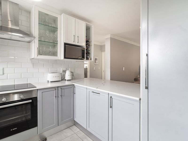 Modern kitchen featuring shaker-style cabinetry, quartz countertops, subway tile backsplash, and integrated stainless steel appliances including an oven and extractor fan.