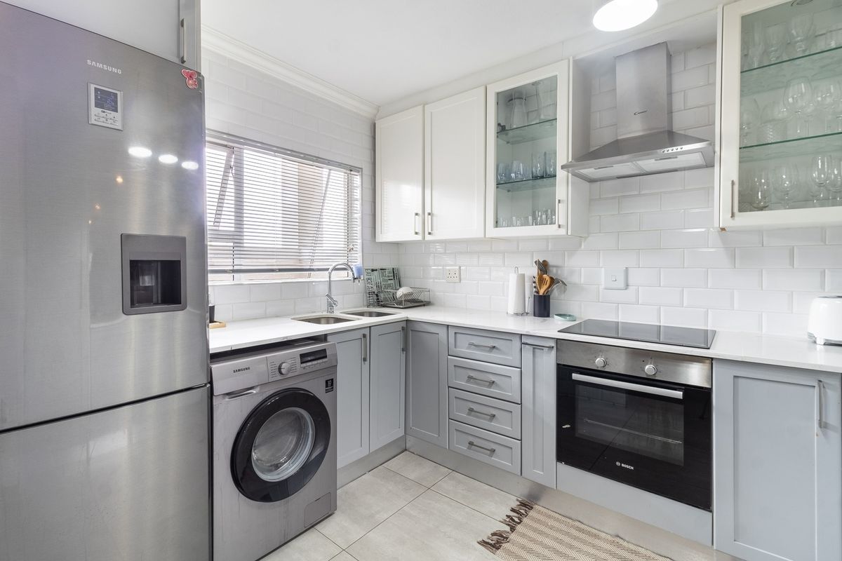 Modern kitchen featuring white subway tile backsplash, shaker-style cabinetry, stone countertops, and integrated stainless steel appliances including an oven and extractor fan.