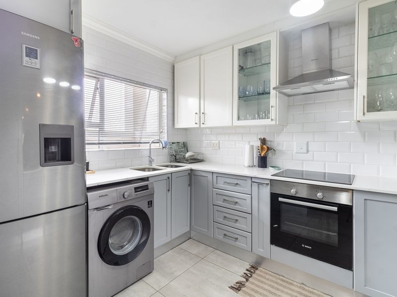 Modern kitchen featuring white subway tile backsplash, shaker-style cabinetry, stone countertops, and integrated stainless steel appliances including an oven and extractor fan.