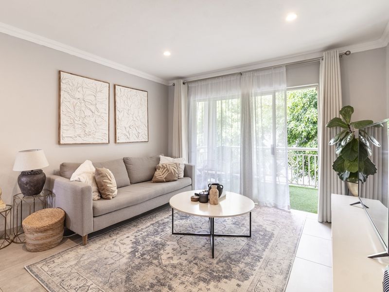 A bright and well-maintained living room featuring tiled flooring, recessed downlighting, and a sliding glass door providing access to an outdoor balcony.