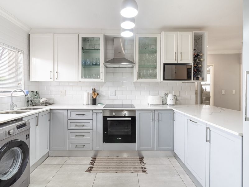 Modern kitchen featuring shaker-style cabinetry, quartz countertops, subway tile backsplash, integrated appliances, and a built-in oven with an electric hob.
