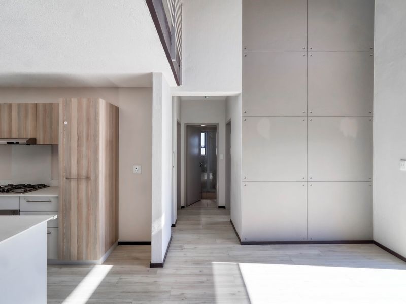 Open-plan living area featuring a modern kitchen with built-in cabinetry, gas hob, and high ceilings with a mezzanine level.