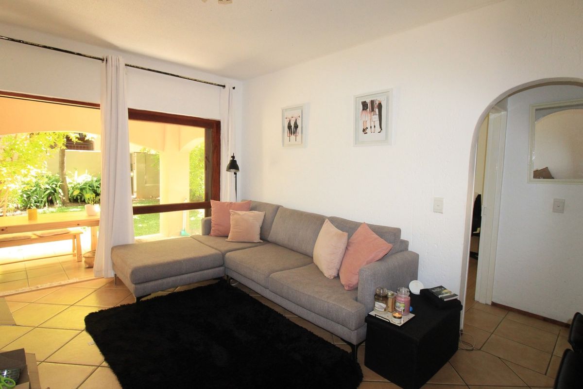 A bright living room featuring tiled flooring, an arched doorway, and a large sliding glass door providing direct access to an outdoor patio area.