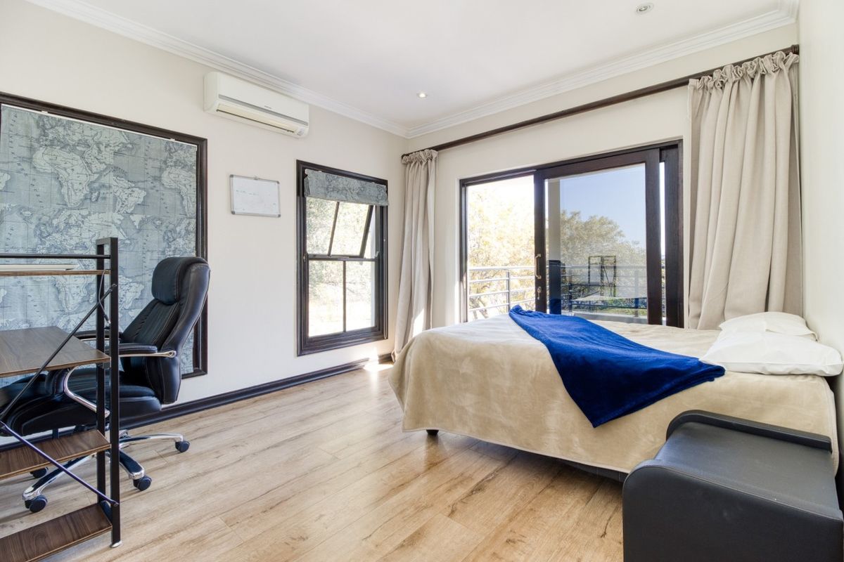 A bright bedroom featuring laminate flooring, a split-system air conditioner, and sliding glass doors that open to an outdoor area.