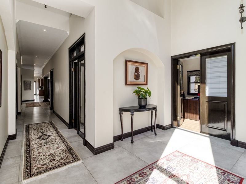 A bright and spacious hallway featuring neutral tiled flooring, dark wood door frames, and an elegant arched wall niche.