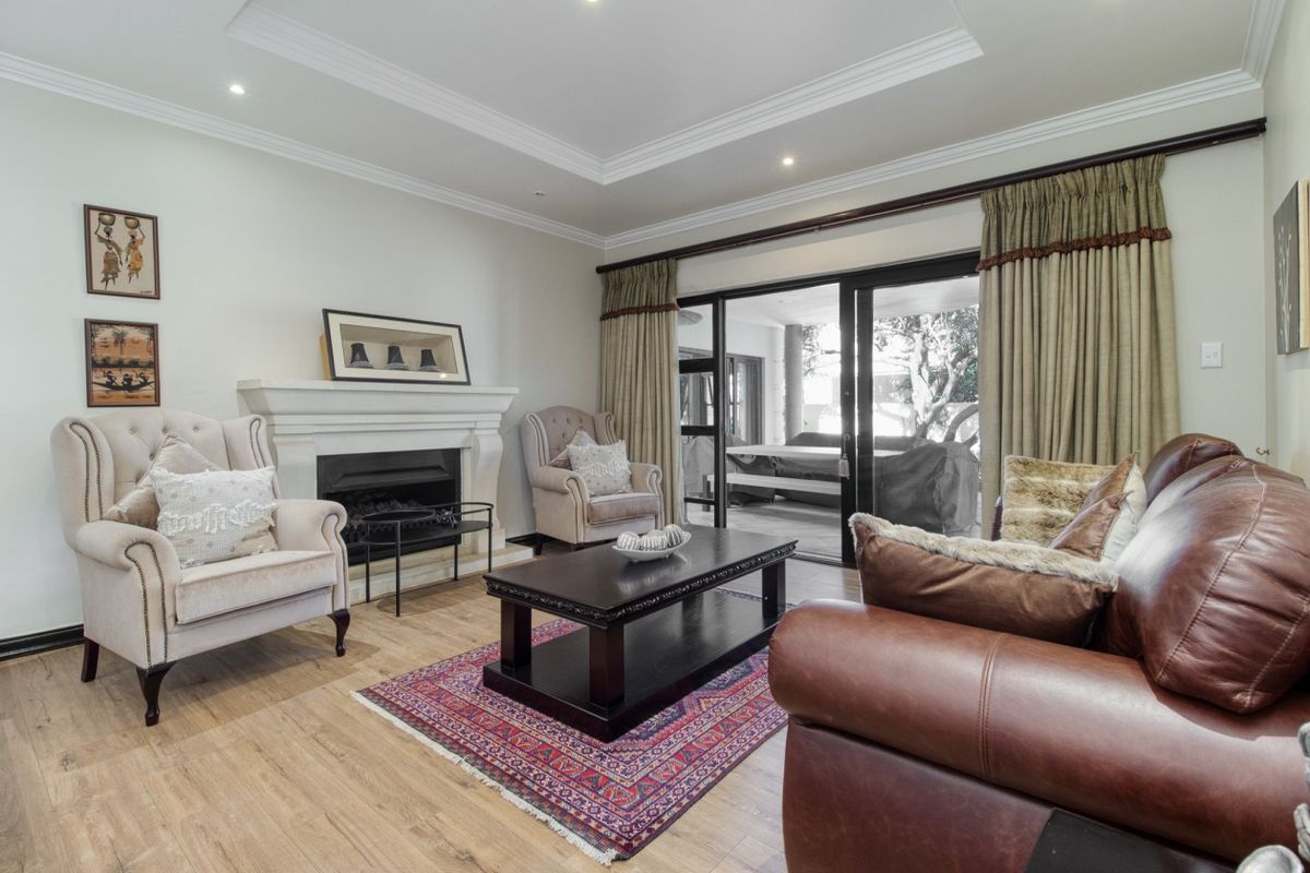A well-maintained living room featuring a classic fireplace, recessed ceiling details, and large sliding glass doors that provide access to the outdoor patio area.