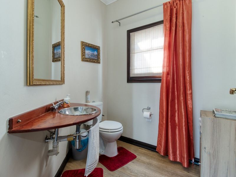A compact bathroom featuring a wall-mounted wooden vanity with a vessel sink, a standard toilet, and laminate flooring.