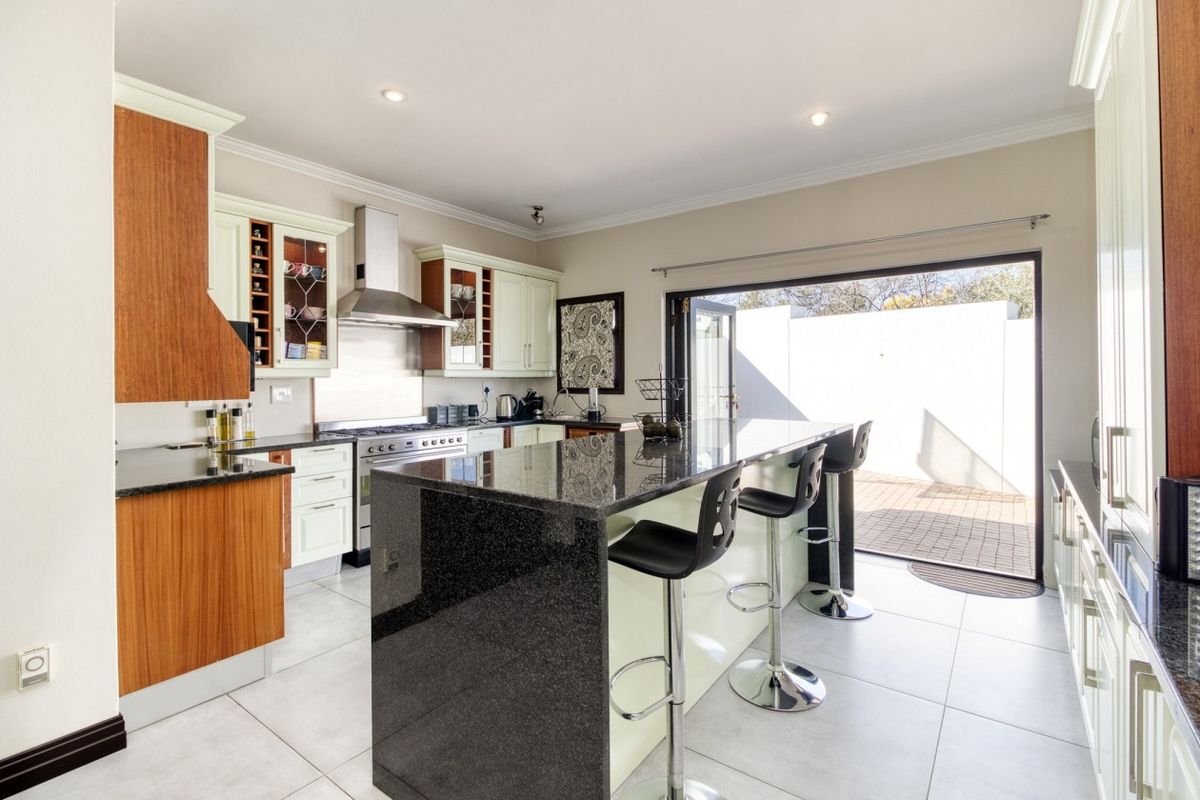 Modern kitchen featuring granite countertops, a central island, stainless steel appliances, and direct access to an outdoor patio area.