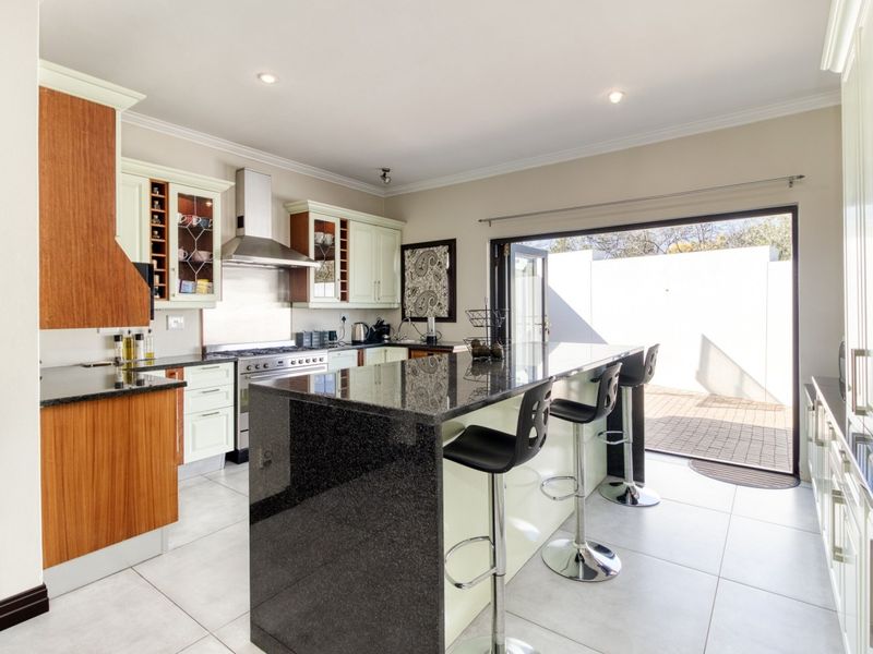 Modern kitchen featuring granite countertops, a central island, stainless steel appliances, and direct access to an outdoor patio area.