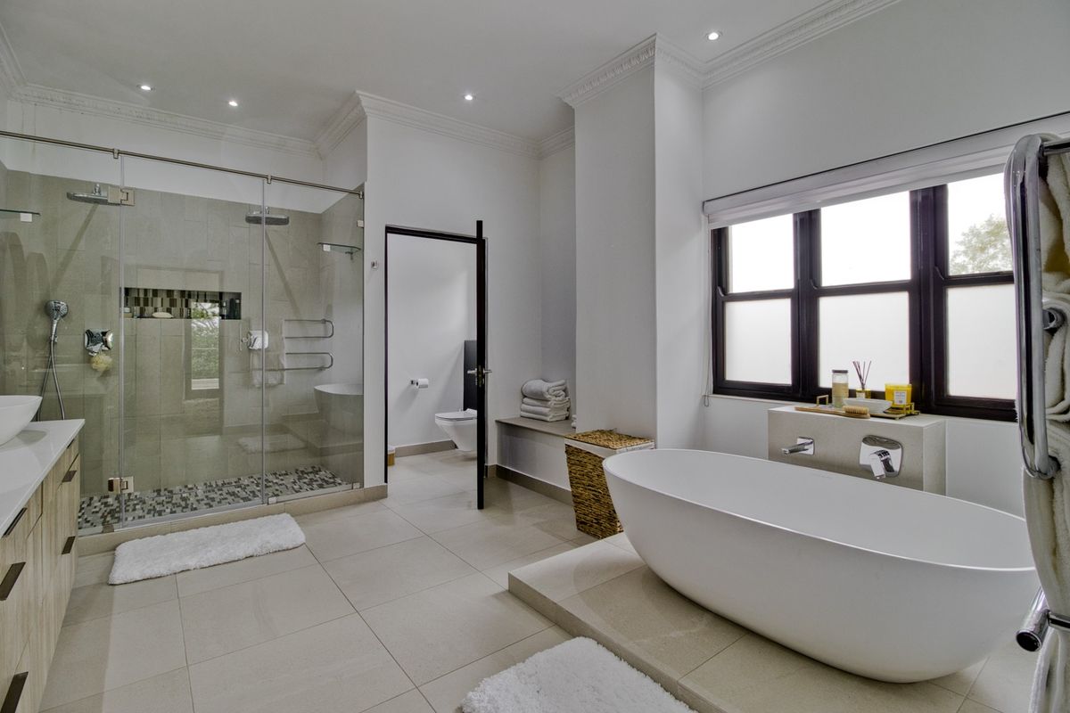 Modern, well-appointed bathroom featuring a sleek freestanding bathtub, spacious walk-in shower with glass enclosure, and contemporary vanity with high-quality finishes.