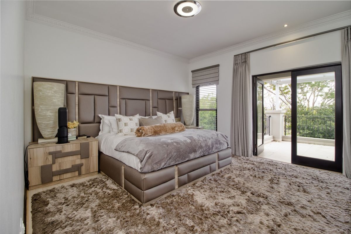 Spacious bedroom featuring a custom built-in headboard, crown molding, and direct access to a private balcony through sliding glass doors.