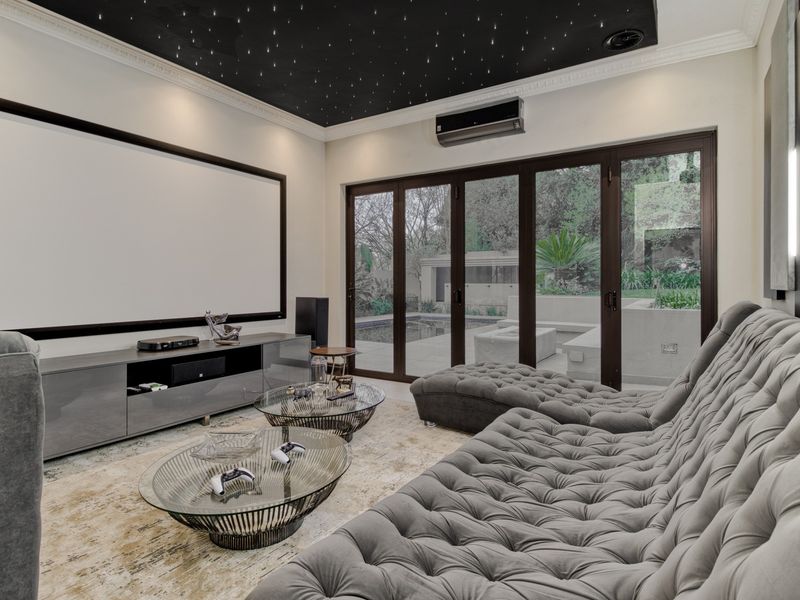 A dedicated cinema room featuring a starlight ceiling, projector screen, and bi-fold doors providing direct access to the outdoor pool area.