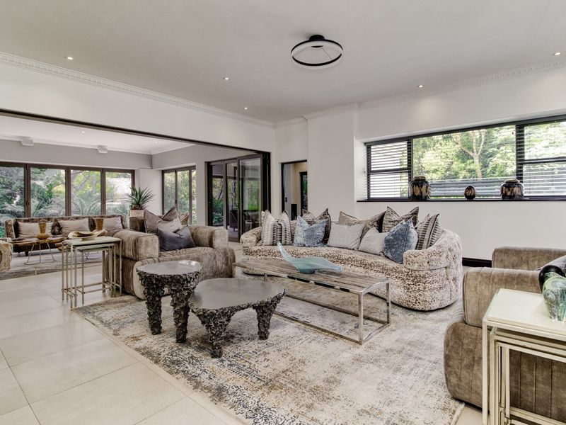 Spacious, light-filled living room featuring large sliding glass doors, tiled flooring, recessed lighting, and elegant cornice detailing, creating a seamless indoor-outdoor flow.