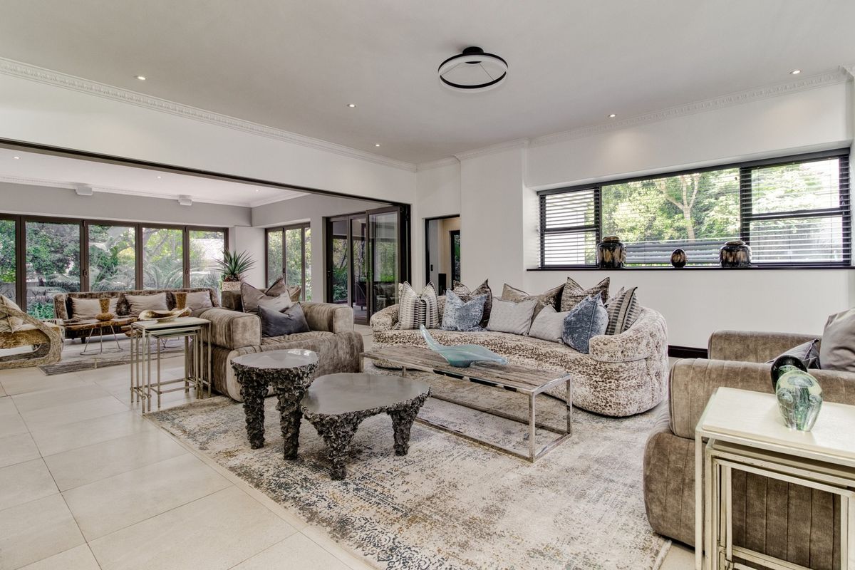 Spacious, light-filled living room featuring large sliding glass doors, tiled flooring, recessed lighting, and elegant cornice detailing, creating a seamless indoor-outdoor flow.